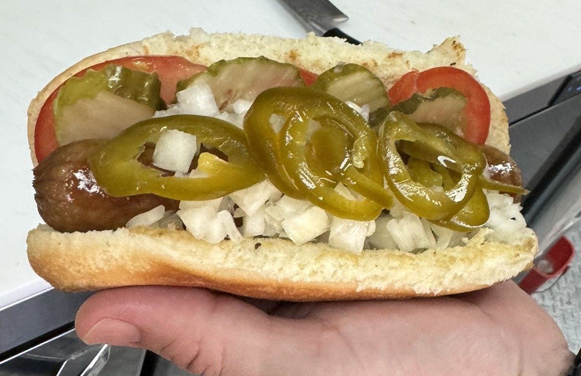 Hot dog with onion, tomato, pickle, and jalapeño